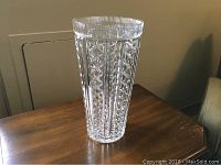 Full view of the large Waterford crystal vase on a wooden table, showing the multifaceted side design and clear crystal material.