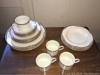 Full set stacked showing cups, plates, saucers with floral and gold trim pattern