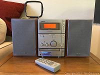 Full view of Sony mini music system with left and right removable speakers placed on a wooden surface, remote control in front.