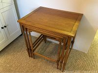 Stacked view of three wooden nesting tables showing tabletop design, legs, and size.