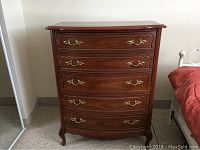 Front view showing five bow front drawers with brass handles and cabriole legs
