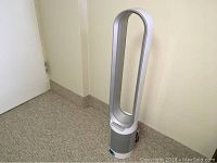Dyson bladeless tower fan standing upright against wall