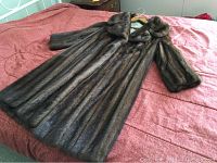Full view of the brown fur coat laid flat on a bed, showing length and silhouette.