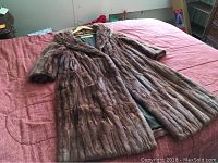 Full view of brown vintage fur coat laid out flat showing short sleeves and length
