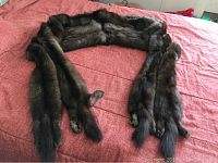 Full length view of the brown natural fur stole laid out on bed showing overall shape and condition.