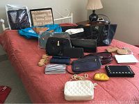 Assorted assorted handbags, purses, and travel bags arranged on a red bedspread