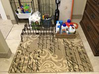 View of carpet, wire racks, cleaning products including detergent bottles and paper towels.