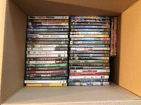 Box of DVDs seen from top showing titles like The War Within, Scouts Honor, The American, The Wild Bunch and many more stacked standing up.