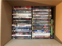 Photo of a box with DVDs showing titles like Runaway Jury, From Hell, Fighting Tommy Riley, Mr Warmth, Interview with the Assassin, Red Lights, and Fat Spy.