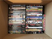Top-down photo of approximately 40 DVDs stacked vertically in their cases inside a box with titles visible.