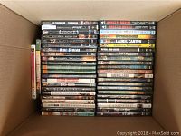 Box filled with neatly stacked DVDs with visible titles such as 'The Terminator', 'Descent', 'King Kong', and 'Auto Focus'