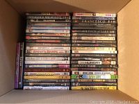 Photo of DVDs stacked in a cardboard box, showing titles like Fiend, Sherlock Holmes, Halloween, Dark, Dennis Allen Show, American Beauty, Without Evidence, Barkley’s Billions, Bronte Country