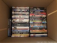 Overhead view of DVDs neatly stacked inside a box showing partial titles like 'Cheech & Chong', 'Family Business', 'Easy', and 'Gas'.