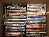 Top view of DVDs arranged in a box showing movie titles in two columns including 'Harry Brown', 'The Last Samurai', 'Outrageous!', 'Alias Disc Four', and others.