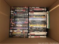 Box of approximately 90+ pre-owned DVDs with various movie titles in plastic cases