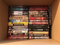 Top view of multiple boxed DVD series and movie collections inside a shipping box held together in rows, showing series titles including Miami Vice, Borgias, Dead Zone, Veronica Mars, The Commish, and others.