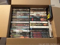 Box of DVDs, showing various movie and TV titles such as Malcolm X, Shark City, Farrah Fawcett, Lord of War, Punch-Drunk Love, Brad Pitt - Too Young to Die?, Mobster Movies box set, and The Unit.