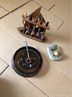 Image showing five vintage wooden pipes arranged on a wooden stand resembling a sailboat, a brown glass ashtray with a wooden pipe placed inside, and a green stone ashtray carving with lighter.
