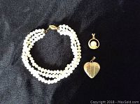 Triple strand freshwater pearl necklace with 14k gold clasp and two gold pendants (heart-shaped and round with pearl).