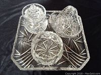 Complete set of four clear pinwheel cut crystal pieces displayed on black cloth.