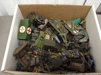 Box filled with assorted vintage plastic army toys and vehicles.