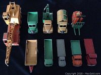 Overview layout of all the Dinky diecast vehicles arranged on a black background showing a mix of crane trucks, flatbeds, tanker, forklift and cargo trucks.