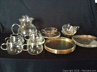 Overview of all glass items including clear glass cups, saucers, plates, gold rimmed lunch plates and a pitcher.