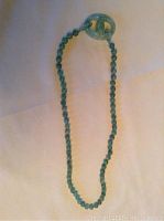Full view of the 30 inch jade beaded necklace with carved knotted pendant shown on light background.