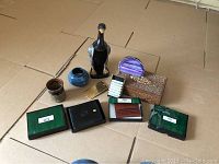 Overview of Men's lot showing pottery, wooden carved box, duck-shaped clothing brush, two leather wallets in boxes, and travel brush