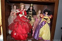 Five Franklin Heirloom porcelain dolls displayed in a wooden shelving cubby, showing full size and gowns.