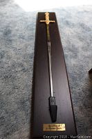 Full view of the sword mounted on the wooden plaque showing the entire sword length and plaque size.