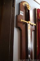 Full view of sword and wooden plaque mounted on wall