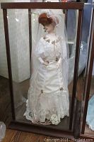 Full view of porcelain Gibson Girl Bride doll in detailed white lace wedding gown inside wood and glass display case.