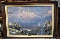 Frontal view of framed lithograph showing mountain vista, lake and waterfall