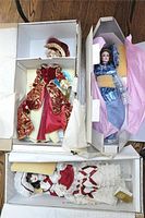 Three porcelain dolls still in original packaging boxes with fabric and bubble wrap protection visible.