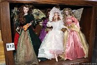 Six Franklin Heirloom angel porcelain dolls displayed behind glass in a wooden cabinet, showing front view with detailed costumes and wings.