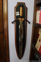 Full view of dagger mounted on wood plaque