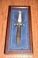 Overhead view of the Viking commemorative knife in its glass-topped wooden display case, showing blue fabric lining and ornate handle details.