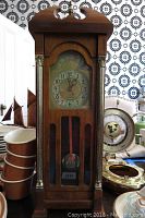 Full view of the wooden mantel clock with decorative metal columns and visible pendulum.