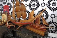 Three wooden model boats displayed on a shelf with different sizes and detailed sails.