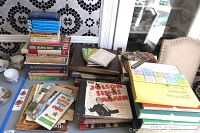Wide shot showing stacks of vintage LP albums, books, and folded maps spread on a table.