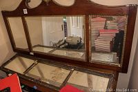Front view of the larger antique mirror showing three glass panels and carved wooden top with gold detailing along inner frame edges. Visible wear including paint chips and cracks on glass.