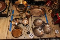 Variety of brass and silverplate items on wooden floor with visible tarnish and signs of age