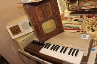 Two vintage radios stacked on each other with keyboard below. Wooden radio housing shows patterned grills and glass panel. Keyboard shows keys with wear.