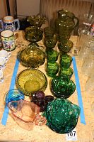 Overview showing a variety of colored Depression glass including green goblets, bowls, pink and blue pieces.