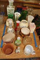 Photo showing a tightly grouped assortment of vases and planters on a table, with various shapes, colors, and materials.