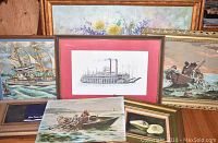 Six artworks arranged with picture frames; ship print, boat paintings, floral paintings, and fruit painting.