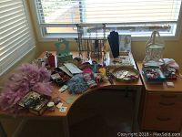 Overhead view of all jewellery and accessories laid out on two desks by a window, includes necklaces on display stands, feather boa, scarves, pins, boxes and a decorative belt.