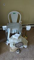 White wicker chair with floral cushion cover, metal towel racks, countertop mirror, bath mats, and towels displayed on carpeted floor.