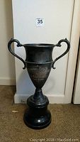 Full view of tall silver plated trophy with handles and pedestal base, showing overall shape and condition.